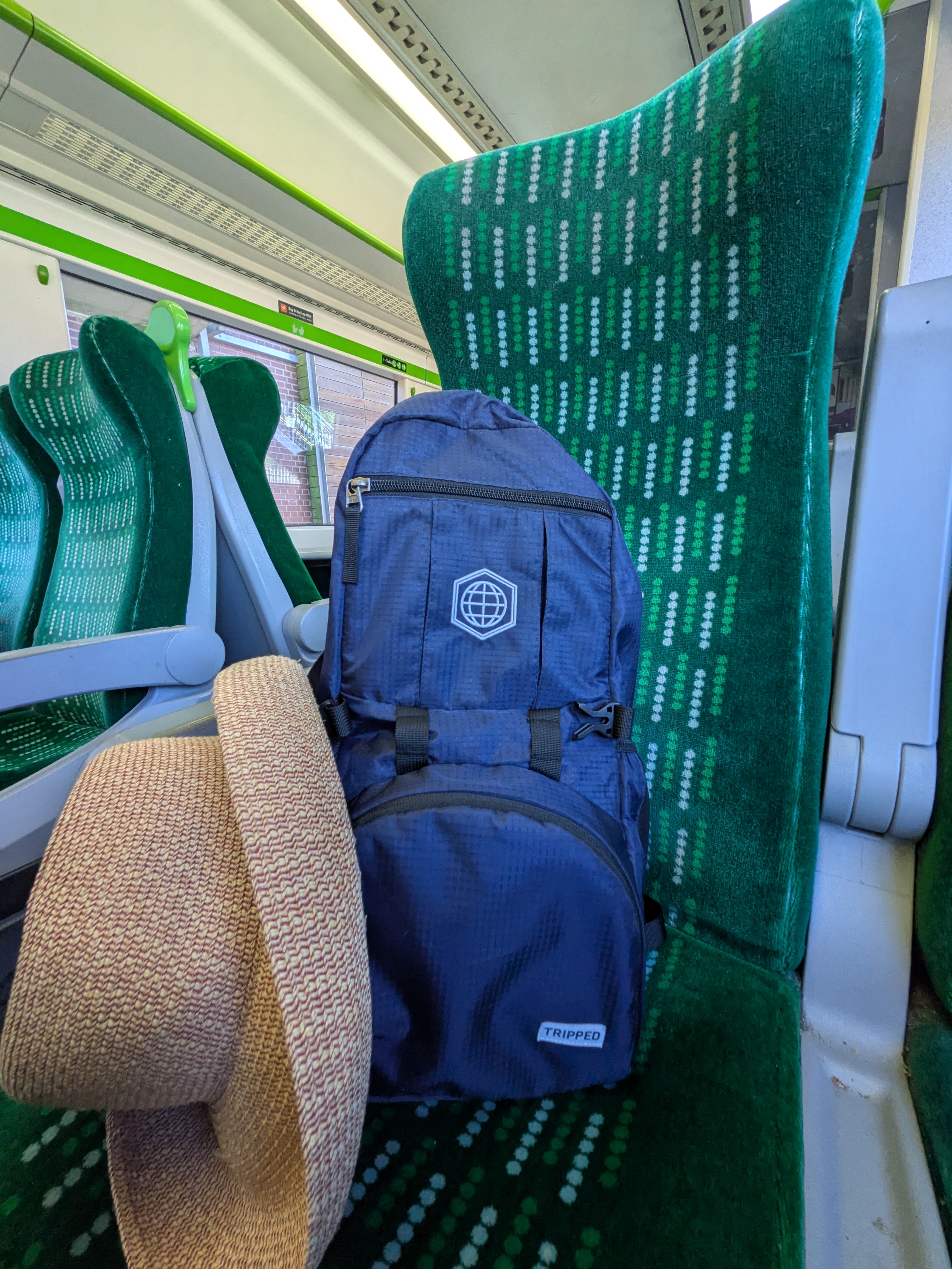 A blue travel backpack resting on a green patterned seat of a modern, clean European train.