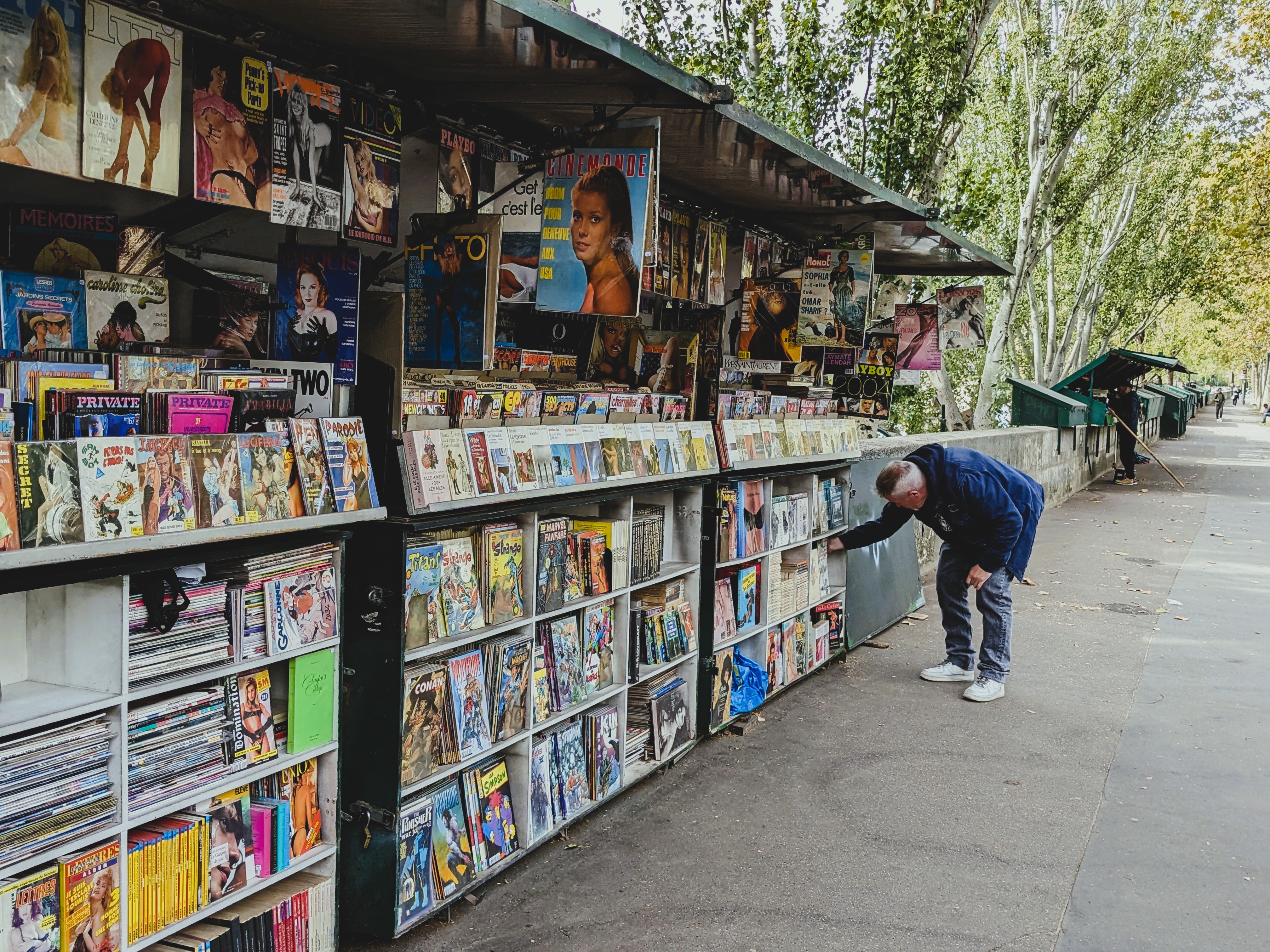 a man stoops to take a closer look at a book at a booksellers stand along the Seine River, a perfect quiet pause in an intentional travel day